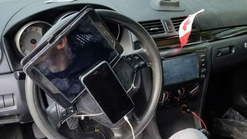 Homem com telemóvel e tablet ao volante
