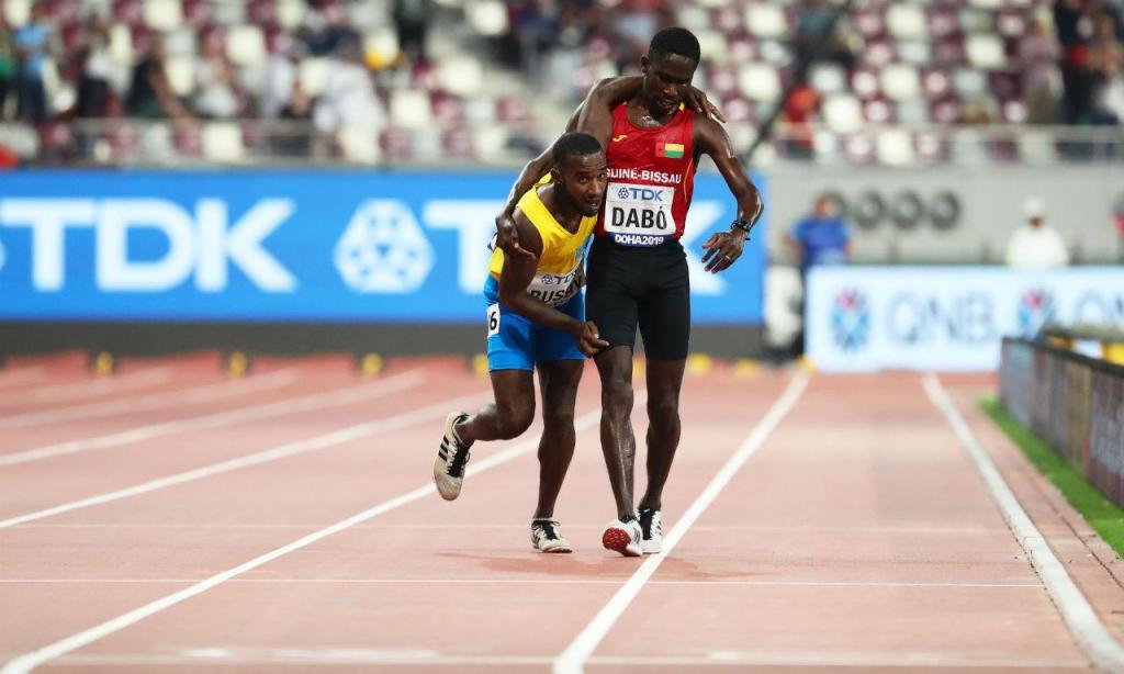 Guineense Dabó carrega arubano Busby até à meta nos Mundiais de Atletismo de Doha (EPA/SRDJAN SUKI)