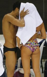 Os nadadores italianos Federica Pellegrini e Filippo Magnini beijam-se por detrás da toalha