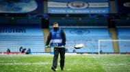 Steward limpa granizo do relvado do Manchester City após tempestade antes do jogo com o PSG (Dave Thompson/AP)