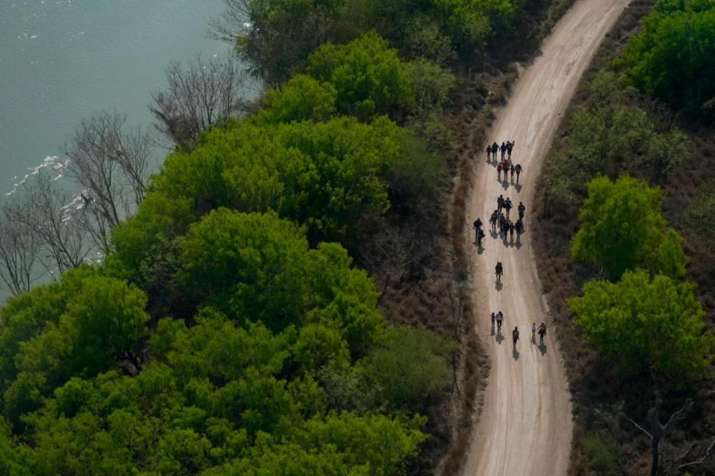 23 de março, migrantes caminham a par do Rio Grande em Mission, Texas, depois de passarem a fronteira EUA-México (Julio Cortez, AP)