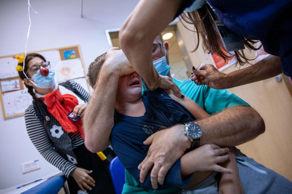 22 de novembro, Ariel Aviran, de 7 anos, chora nos braços do pai ao ser vacina contra a covid-19 no hospital Hospital Sheba Tel Hashomer em Ramat Gan, Israel (Oded Balilty, AP)