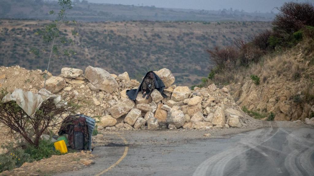 Um soldado do governo etíope sentado num conjunto de pedras criado para bloquear o acesso à estrada que leva a Abi Adi, na região de Tigray, no norte da Etiópia, a 11 de maio de 2021.