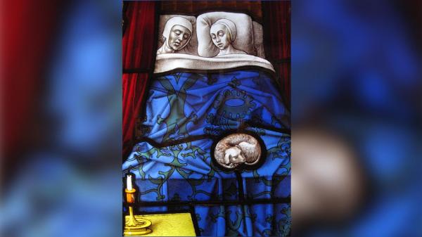 O painel de um vitral numa igreja medieval que retrata um casal a dormir. Foto: TonyBaggett/iStockphoto/Getty Images