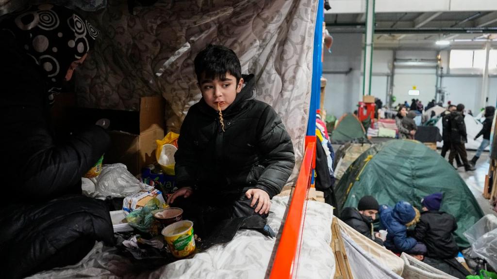 
Criança faz uma refeição enquanto os migrantes se instalam no centro de logística do posto de controlo "Bruzgi" na fronteira Bielorrússia-Polónia