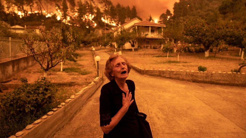 Em agosto, uma mulher idosa foi obrigada a abandonar a sua casa à medida que um incêndio arrasa a ilha de Evia, na Grécia. Foto: Konstantinos Tsakalidis/Bloomberg/Getty Images