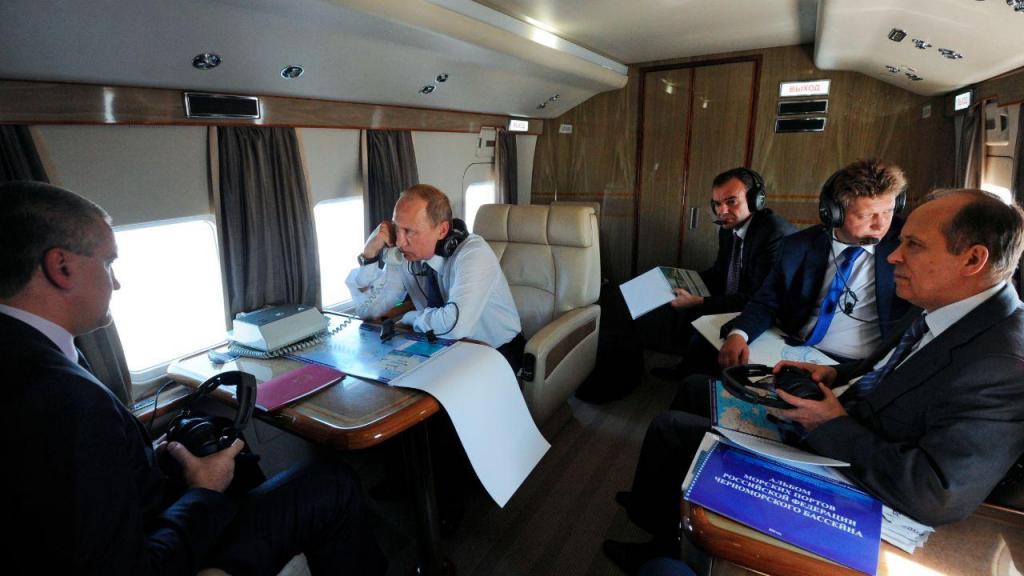 Vladimir Putin a bordo de um helicóptero, em Novorossiisk, sul da Rússia, em 2015. À direita, está o chefe do FSB, Alexander Bortnikov, acompanhado pelo ministro russo dos Transportes (AP)