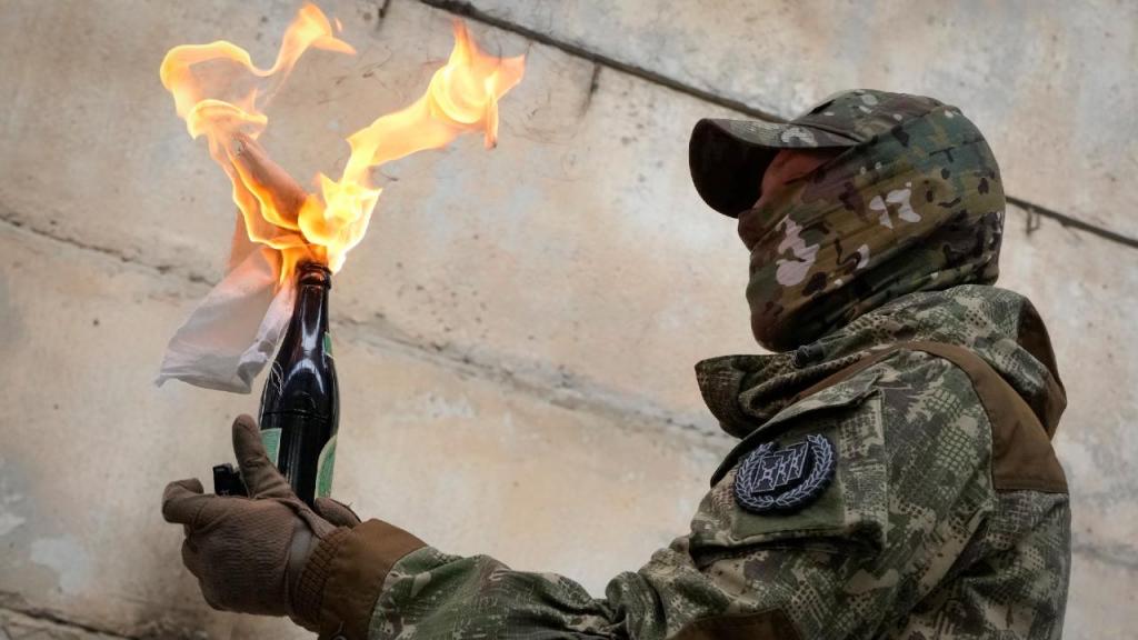 Um cidadão ucraniano prepara-se para usar um cocktail molotov contra uma parede durante uma campanha de treino, perto de Kiev, Ucrânia. "Não entre em pânico! Prepare-se!", disseram-lhe os militares. (AP Photo/Efrem Lukatsky)