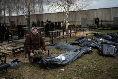 Nadiya Trubchaninova, 70, sentada junto do corpo coberto do filho Vadym Trubchaninov, 48, morto por soldados russos em Bucha. Foto: Rodrigo Abd/AP