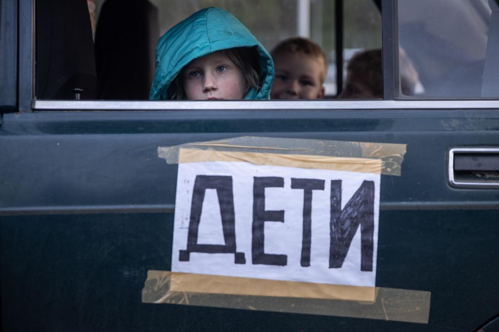 Um rapaz espreita pela janela de um carro que faz parte do comboio humanitário com civis evacuados da região de Mariupol. Foto: Chris McGrath/Getty Images