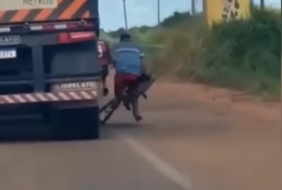 Ciclista à boleia de camião cai (captura YouTube «Truck Force»)