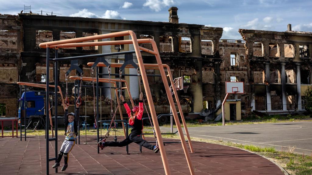 Crianças brincam no parque de uma escola destruída em Kharkiv. 24 maio 2022. Foto: John Moore/Getty Images