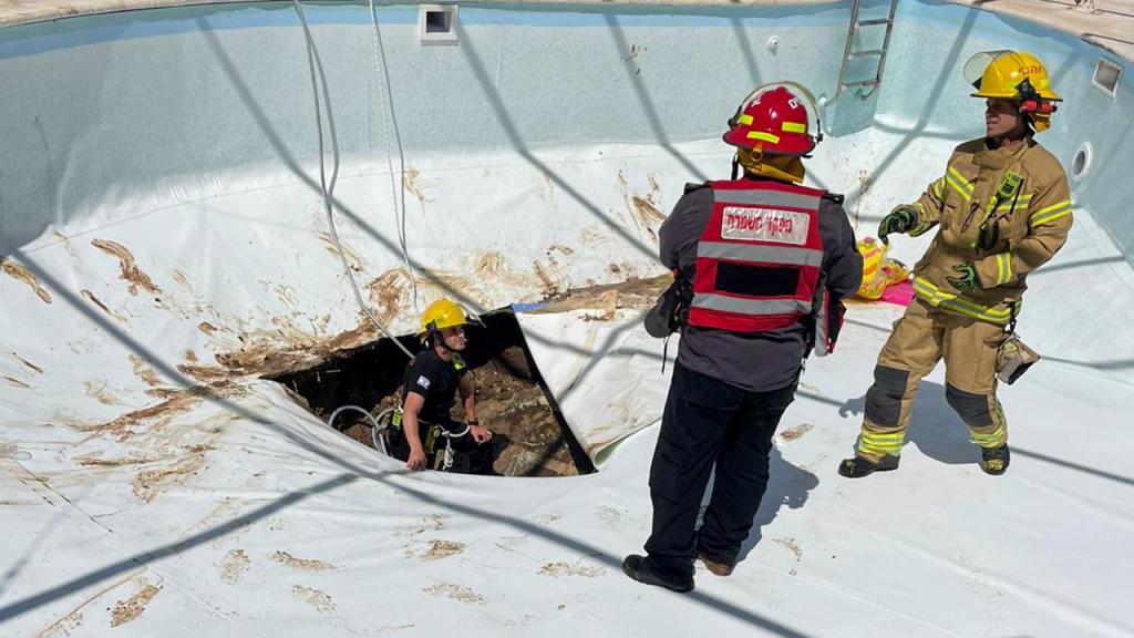 Bombeiros e equipa de resgate junto do buraco formado na pisicina, em Israel. (Israeli Fire and Rescue Services via AP)