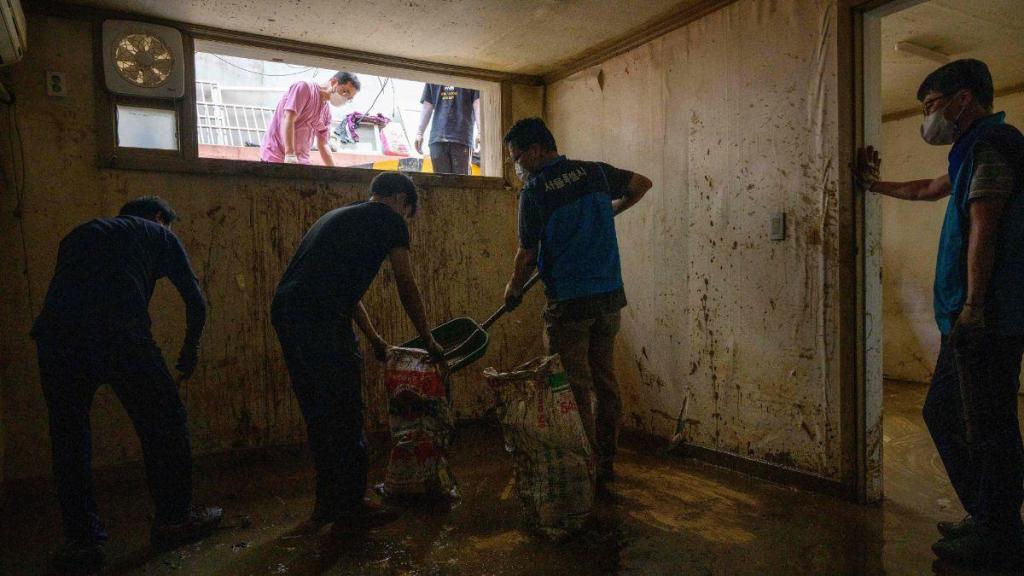 A realidade supera a ficção: trabalhadores limpam uma "banjiha" que ficou inundada no distrito de Gwanak, em Seul, esta quinta-feira. (ANTHONY WALLACE/AFP)