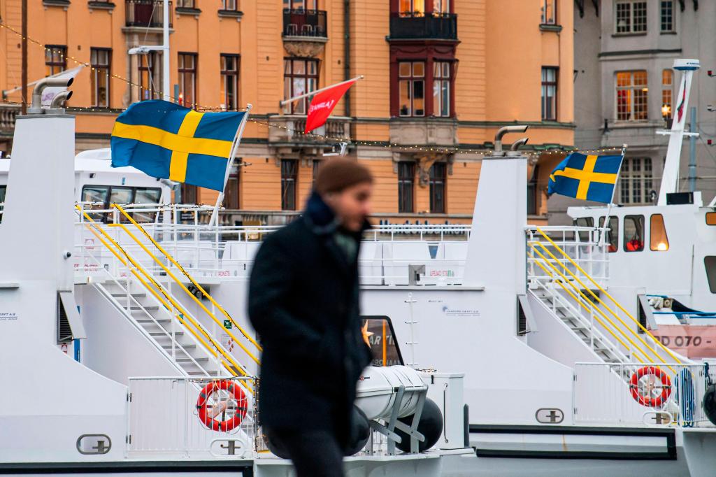 Bandeiras suecas em barcos atracadas no porto de Estocolmo, dezembro de 2020 (Imagem Getty)