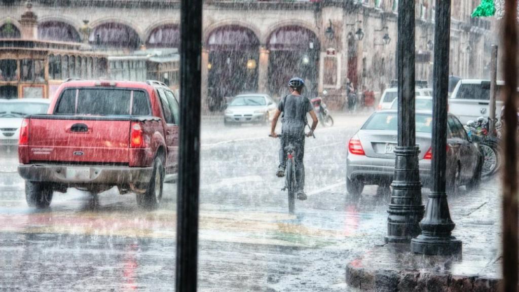 Homem a andar de bicicleta à chuva (Foto: Genaro Servin/Pexels)