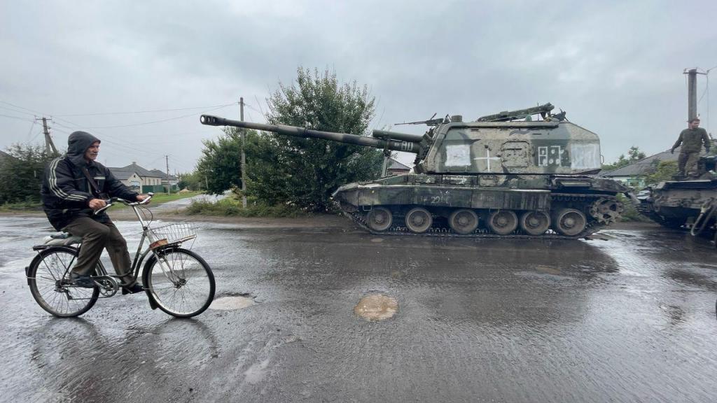 Um homem passa de bicicleta junto a um veículo de artilharia autopropulsor russo abandonado em Izium