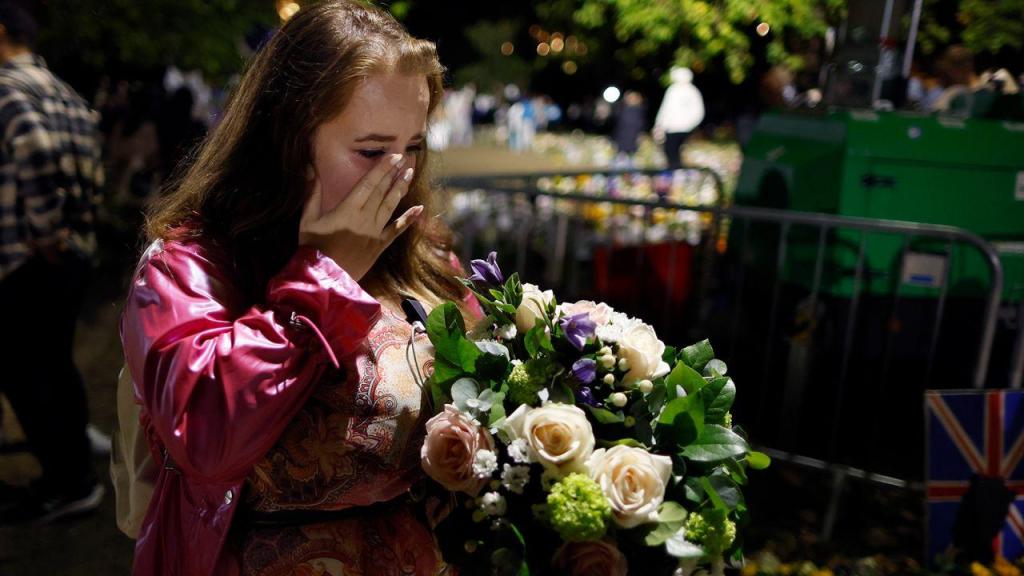 Uma mulher limpa as lágrimas depois de cumprir um minuto de silêncio e reflexão sobre a vida da Rainha Isabel II na zona de tributo floral em Green Park, perto do Palácio de Buckingham, a 18 de setembro, em Londres. (Imagem Getty)
