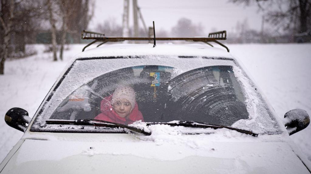 Uma criança aguarda num carro à porta de uma fila para recolher ajuda humanitária em Zelene, na Ucrânia. 18 fevereiro 2023. Foto: AP Photo/Vadim Ghirda