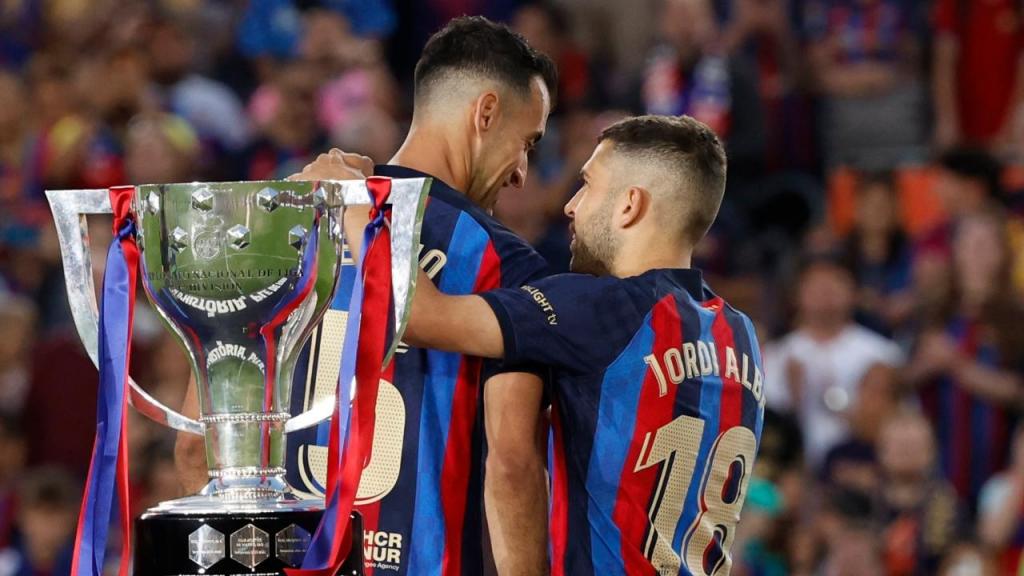Sergio Busquets e Jordi Alba abraçados junto ao troféu da liga espanhola, após o Barcelona-Maiorca que marca a despedida de ambos de Camp Nou (AP/Joan Monfort)