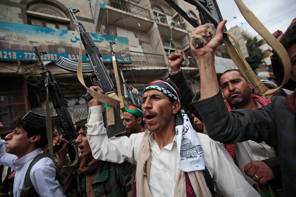 Apoiantes Houthi seguram armas enquanto entoam slogans durante um protesto contra os ataques israelitas aos palestinianos em Gaza, a 17 de maio de 2021, em Sanaa, Iémen. AP Photo _ Hani Mohammed