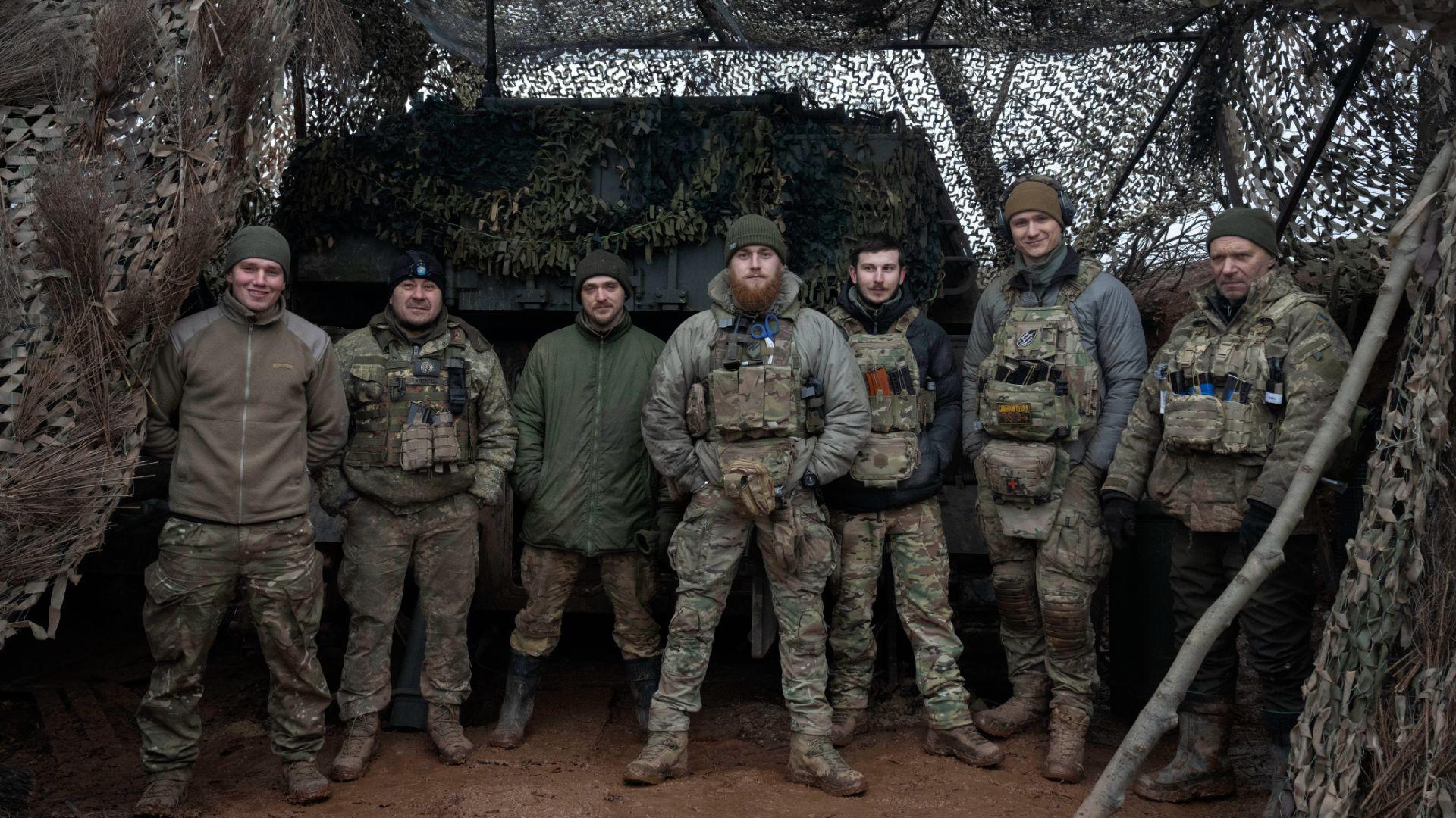 Grupo de soldados da 12ª Brigada de Forças Especiais da Brigada Azov posam para uma fotografia junto a um blindado de artilharia na linha da frente, perto de Kreminna, na região de Lugansk (AP Photo/Efrem Lukatsky)